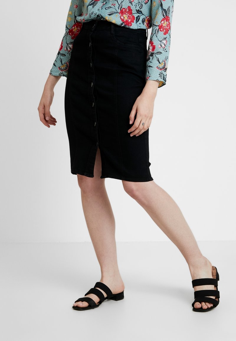 Musta farkkuhame, jossa on edessä halkio ja napitettava kiinnitys, yhdistettynä kukkapainokuvioiseen yläosaan ja mustiin remmisandaaleihin.