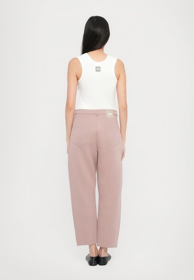 Ανοιχτό ροζ παντελόνια με φαρδιά γραμμή, κατασκευασμένα από απαλό ύφασμα και διαθέτουν δύο πίσω τσέπες. Συνδυασμένα με ένα λευκό αμάνικο τοπ που έχει λογότυπο στην πλάτη.