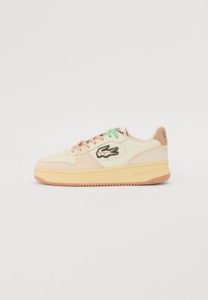Zapatilla deportiva color blanco hueso con detalles beige y durazno, cordones verdes y durazno, suela de goma y logo de cocodrilo de Lacoste en el lateral.