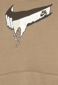 Felpa marrone con un grande logo Nike SB che gocciola in bianco e nero. Texture liscia con sfondo di colore uniforme.