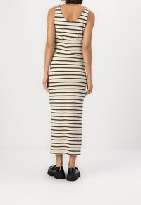 Strapless, beige and black striped dress, form-fitting design, mid-calf length, soft fabric, paired with chunky black shoes.