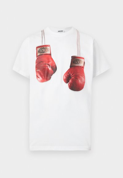 Άσπρο βαμβακερό μπλουζάκι με γραφικό σχέδιο κόκκινων γαντιών πυγμαχίας, διακοσμημένο με μπεζ λουριά και το όνομα της μάρκας «Moschino» στα γάντια.