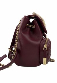 Piccolo zaino in pelle borgogna con spalline a catena dorate, tasca con zip frontale e dettaglio decorativo di perle sul flap superiore.