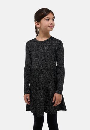 Robe noire à manches longues avec une texture côtelée, dotée d'un décolleté festonné et d'un ourlet évasé. Portée avec des leggings noirs.