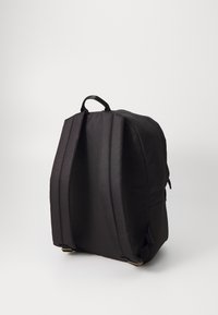 Sac à dos noir en tissu texturé, avec des bretelles rembourrées et ajustables, une poignée supérieure et un design rectangulaire épuré.