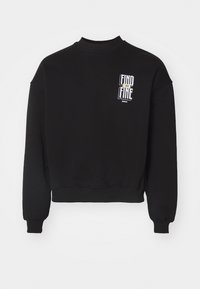 Svart cropped sweatshirt laget av myk stoff. Har ribbestrikket hals og ermer. Front til venstre viser en grafisk tekstdesign i hvitt og gult.