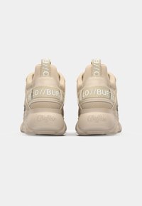 Béžové tenisky s hladkým povrchem, s bílým logem na patě a výraznými silnými podrážkami pro tlumení a podporu.