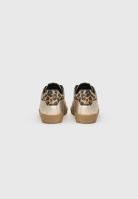 Sneakers metallici dorati con finitura texture, caratterizzati da accenti leopardati sul retro e una suola in gomma marrone. Design classico a bassa altezza.