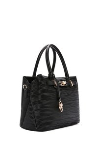 Black handbag with wavy textured pattern, double handles, gold-tone clasp, and hanging decorative charm on the front side.