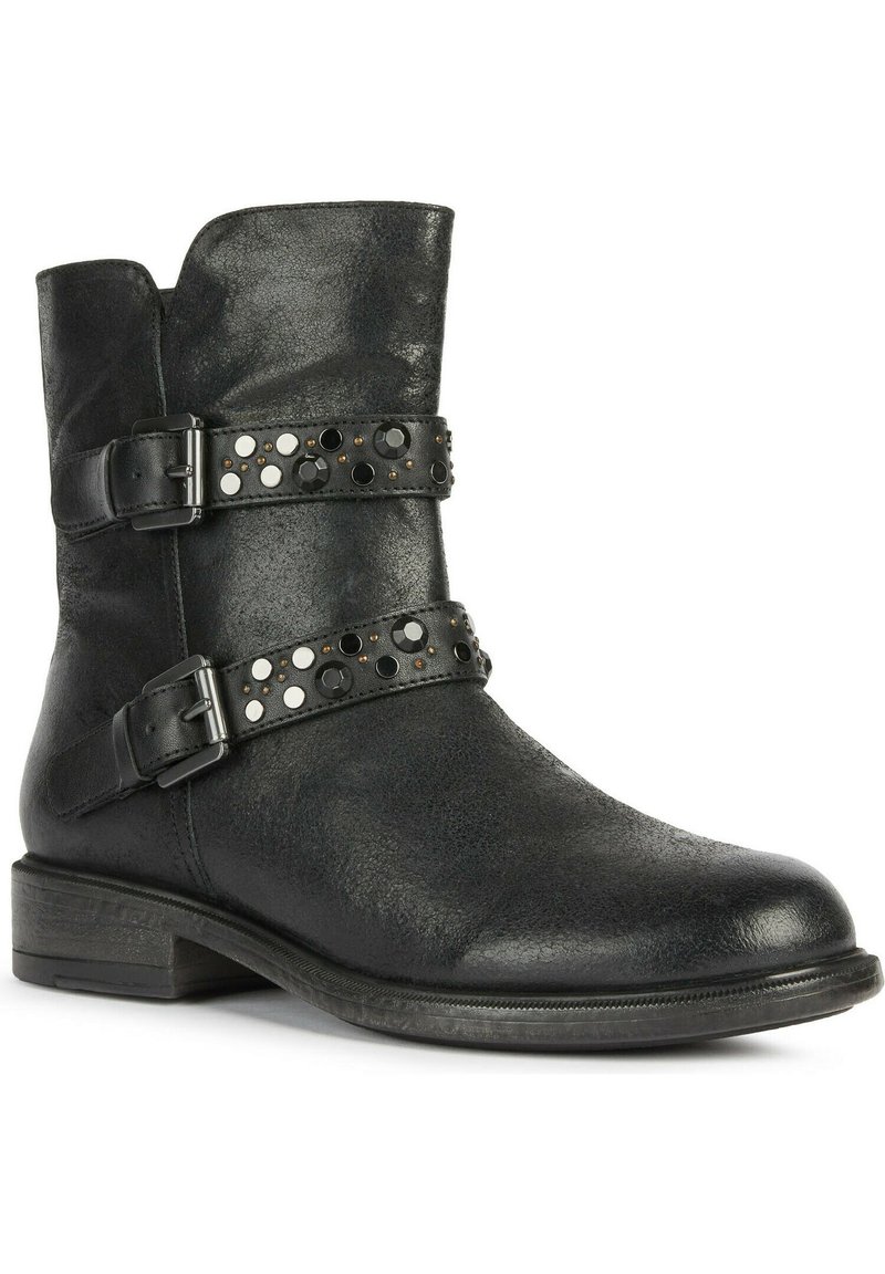 Bottine en cuir noir avec deux sangles décoratives. Présente des clous argentés et noirs. Design structuré et petit talon empilé. Fini texturé.