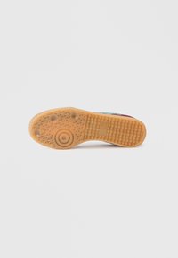 Dampju gumijas zolīte ar reljefu rakstu, kurā ir redzams apļveida dizains. Galvenā krāsa ir bēša, nav redzamu zīmolu vai logotipu.