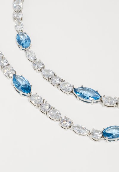 Silver-tone necklace featuring alternating marquise and round blue and clear gemstones, showcasing varying shades and sizes.