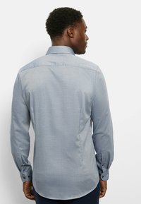 Hellblaues Hemd mit langen Ärmeln und strukturiertem Muster, geknöpfte Manschetten und klassischer Kragen. Verfügt über einen abgerundeten Saum und eine taillierte Passform.