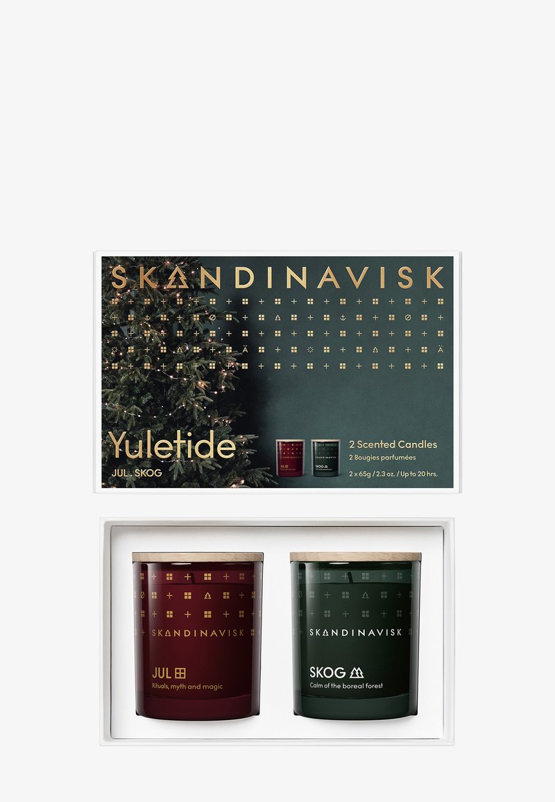 Kaksi tuoksukynttilää valkoisessa laatikossa. Toinen on syvän punainen lasi kultaisilla yksityiskohdilla; toinen on tummanvihreä puukannen kanssa.