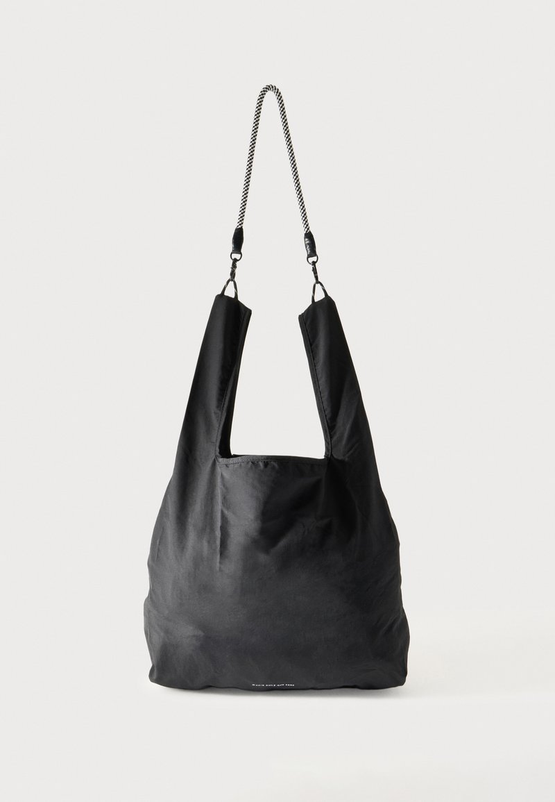 Sac fourre-tout en tissu noir doux avec de larges anses et une fine bandoulière tressée noire et blanche.