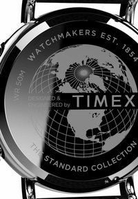 Round silver watch case features a black globe design on the back, with "TIMEX" in bold and "DESIGNED & ENGINEERED" above. Water-resistant to 50m.