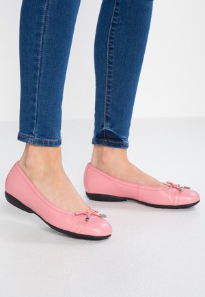 Bailarinas rosas de cuero con punta redonda, detalles de lazo decorativo y suela de goma negra, combinadas con jeans ajustados azules.