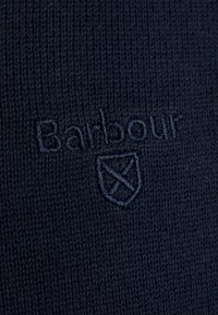 Tissu en maille bleu marine à texture lisse arborant le logo "Barbour" et l'emblème du bouclier brodés dans une couleur de fil assortie.