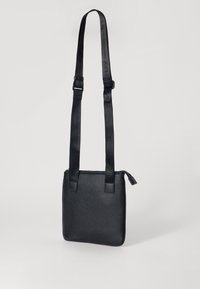 Borsa a tracolla nera in pelle con superficie texturizzata, spallacci regolabili, chiusura a zip e forma quadrata. Design minimalista senza ulteriori decorazioni.