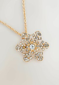 Gold-tone necklace featuring a snowflake pendant adorned with sparkling clear and a single yellow rhinestone, intricate floral design.