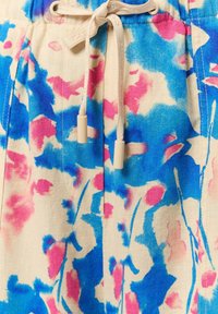 Blumenmuster-Shorts aus leichtem Stoff. Sie haben eine cremefarbene Basis mit blauen und rosa Spritzern, einen elastischen Bund und einen Kordelzug.