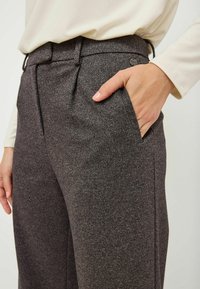 Grijze visgraatbroek met zijzakken en een getailleerde pasvorm. De stof heeft een gestructureerde afwerking, aangevuld met een contrasterende tailleband.