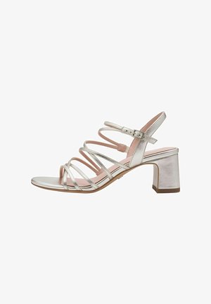 Strappy heeled sandal with silver metallic finish, open toe, and block heel. Features slender straps with an adjustable buckle at the ankle.