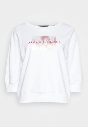 Biała bluza z długim rękawem z okrągłym dekoltem i różowym napisem "Armani Exchange" na rozmytym prostokątnym wzorze na piersi.