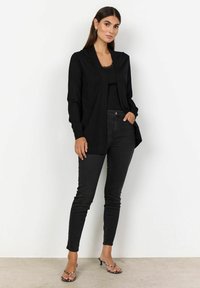 Melna garu piedurkņu kardigāns ar šals apkakli, kombinēts ar melnu topi un augsto jostasvietu melniem skinny džinsiem. Akcentēts ar dzīvnieku raksta sandālēm.