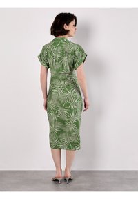 Grünes Kleid mit einem Blattmuster, kurzen, flatternden Ärmeln, tailliertem Schnitt und einem knielangen Saum. Aus leichtem Stoff mit einer strukturierten Oberfläche.