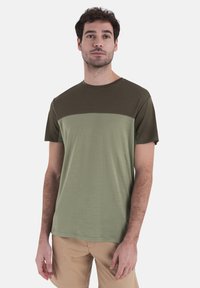 T-shirt a maniche corte con design bicolore, parte superiore verde scuro e parte inferiore verde chiaro, realizzato in tessuto morbido.