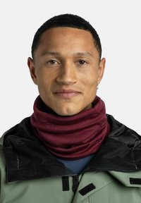 Maroon neck gaiter made of soft fabric, worn by a person with a black and green jacket, featuring a zip and Velcro accents.