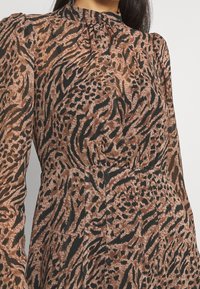 Klänning med brunt och svart djurmönster, hög krage, långa ärmar och plisserade detaljer, tillverkad av ett genomskinligt, lätt material.