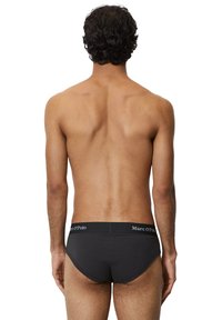 Schwarze Slips mit weichem Bund und weißen "Marc O'Polo"-Logos; nahtloses Design und figurbetonte Form.