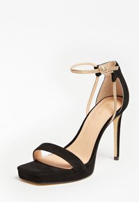 Sandale à talons hauts en daim noir avec un bout carré, deux lanières croisées et une fine lanière de cheville avec une boucle métallique et un détail découpé.