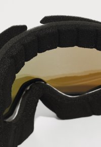 Gros plan de lunettes de protection à coussin en mousse noire et teintées de jaune, conçues pour protéger des impacts et de la poussière.
