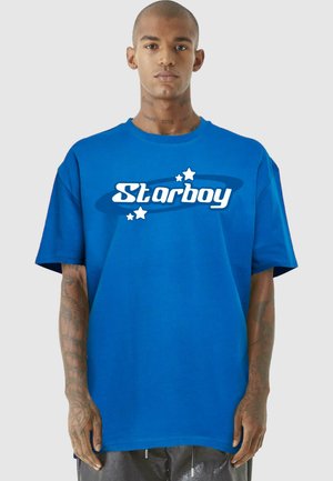 Mėlynas medvilninis marškinėliai trumpomis rankovėmis, su "Starboy" logotipu balta spalva, kuriame yra grafinių elementų ir žvaigždžių apvalioje dizaino formoje.