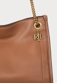 Καφέ δερμάτινη τσάντα χειρός με υφή, διαθέτει χρυσό αλυσίδα και κυκλικό λογότυπο με την επιγραφή "Ralph Lauren".