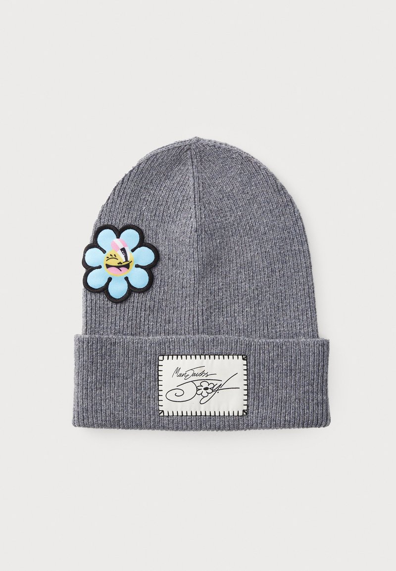 Bonnet en tricot côtelé gris avec un revers, orné d'un patch en forme de fleur bleue avec un visage souriant et d'une étiquette blanche avec du texte et des coutures noires.