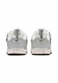 Une paire de baskets Nike blanches vues de l'arrière, avec un tissu en maille, un motif géométrique et des logos Swoosh Nike noirs.