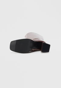 Sapato de salto alto em pele castanha com parte superior em tecido suave rosa, bico quadrado e sola de borracha preta texturizada, apresentando um salto bloco baixo.