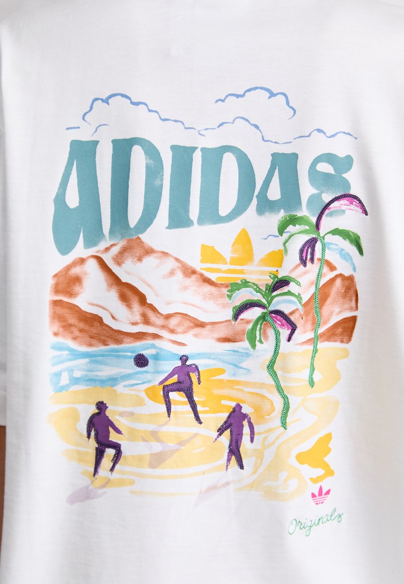 Wit katoenen T-shirt met een kleurrijke afbeelding waarop de tekst "ADIDAS" staat, samen met een strandtafereel met palmbomen en gestileerde figuren.