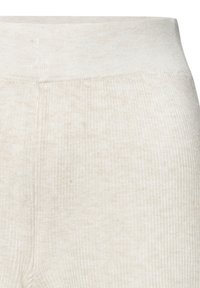 Light beige ribbed leggings with a wide elastic waistband. Soft texture, fitted shape, and subtle variations in the fabric color.