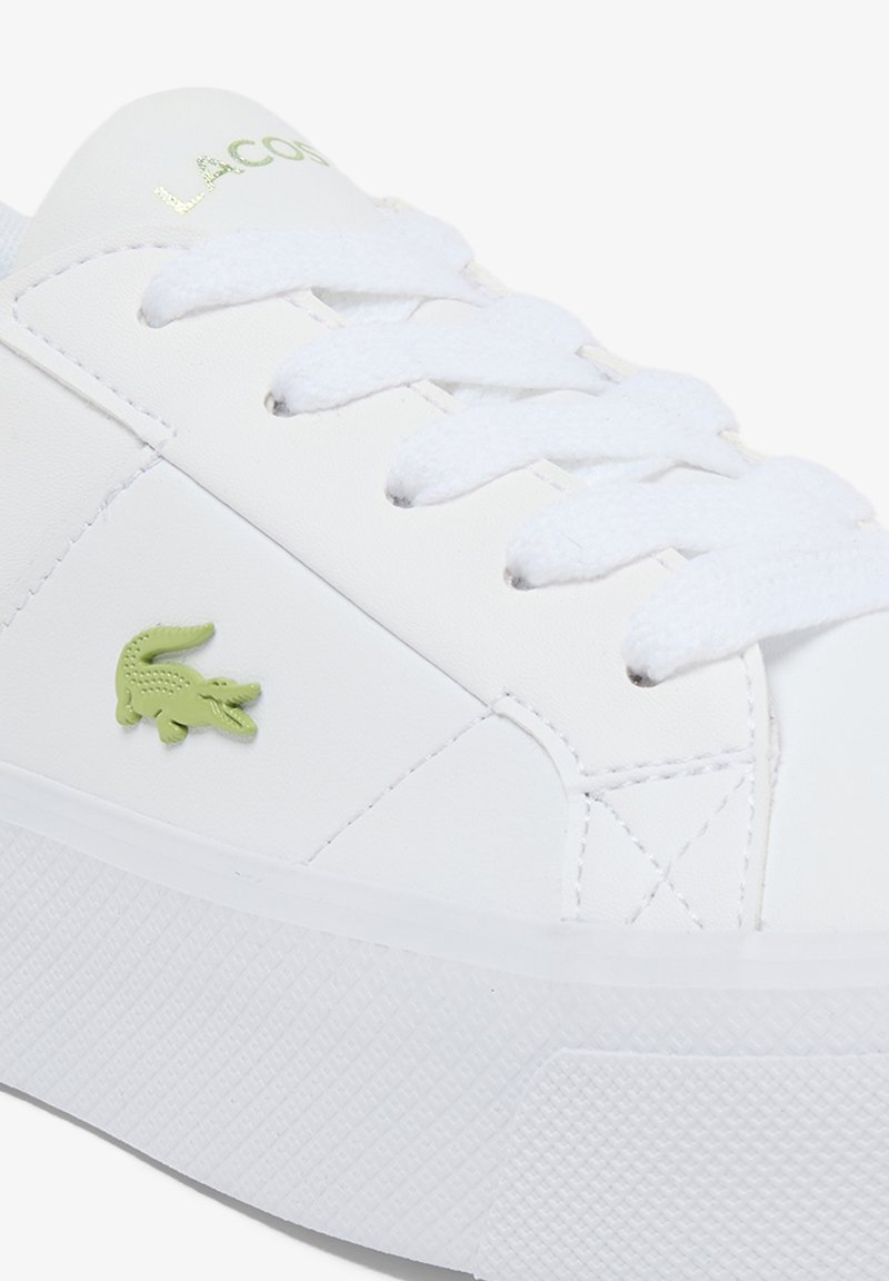 White Lacoste sneaker with white laces, a green crocodile logo on the side, and "LACOSTE" text in green on the tongue.