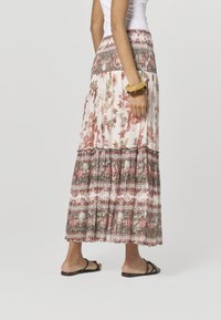 Maxihame, jossa on kukkakuvioita vaaleanpunaisen ja vihreän sävyissä, laskostettu malli, joustava vyötärönauha ja kerrokselliset röyhelödetaljit.