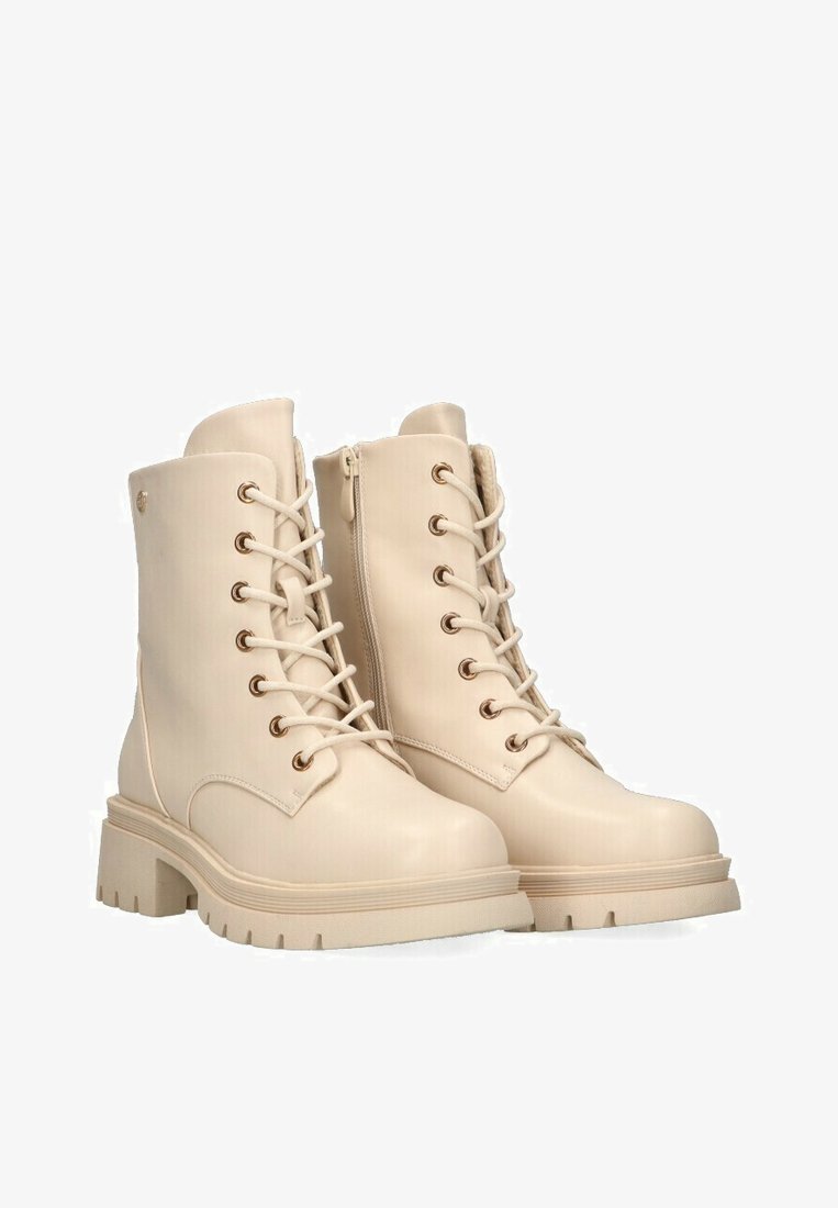 Botas de tobillo beige hechas de material sintético suave. Cuenta con ojales de metal, cordones en la parte delantera y una suela gruesa y texturizada.