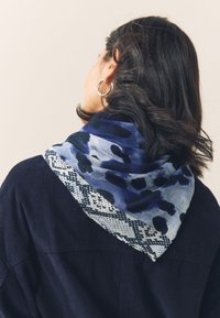 Multicolored scarf featuring a blue and gray abstract pattern with darker accents, finished with a textured border. Lightweight fabric drapes softly.