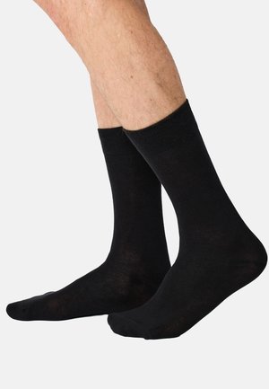 Czarne skarpetki za kostkę ze ściągaczami, wykonane z miękkiej, gładkiej tkaniny. Charakteryzują się klasycznym designem bez widocznych wzorów ani ozdób.