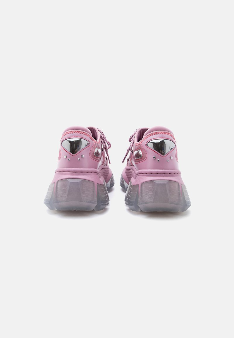 Paar klobige rosa Sneakers mit transparenten, dicken Sohlen, metallischen Akzenten an den Fersen und rosa Schnürsenkeln, von hinten auf weißem Hintergrund gesehen.