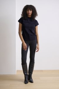 Haut noir à manches courtes associé à un jean skinny noir. Bottes en cuir noires montantes. Design simple, texture lisse et coupe ajustée.